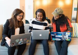 Tri ženske s prenosniki na tečaju slovenščine ZIP. Integracija priseljencev.