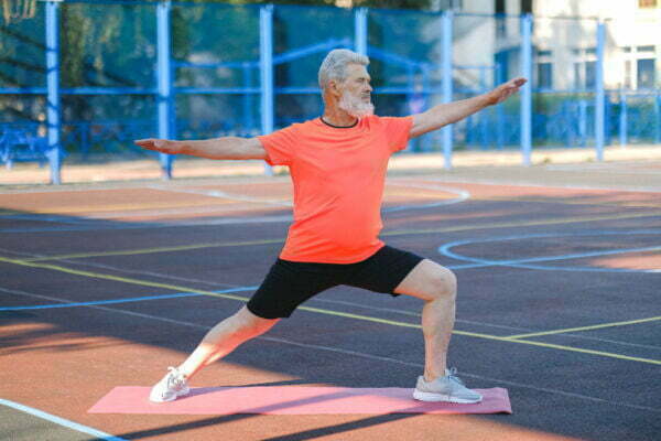 Starejši moški izvaja jogo na prostem. Joga za seniorje, aktivno staranje, zdrav življenjski slog.
